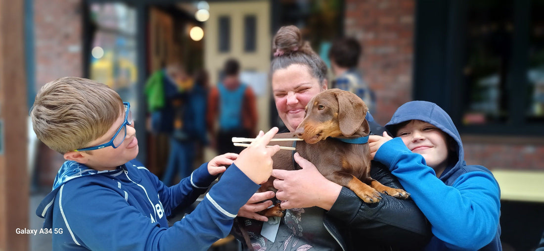 Mum holding a little dog with 2 kids. 